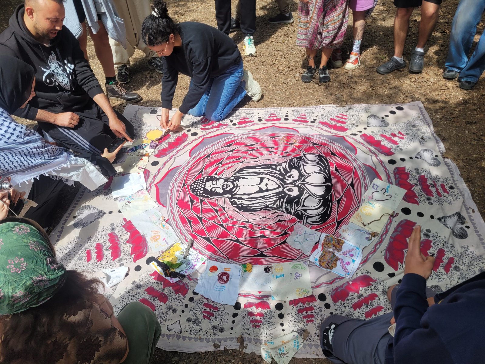 Les jóvenes de Focus Pocus se reúnen alrededor de un mapa colectivo de tela, creado a partir de piezas individuales con dibujos y símbolos que representan sus caminos de aprendizaje.