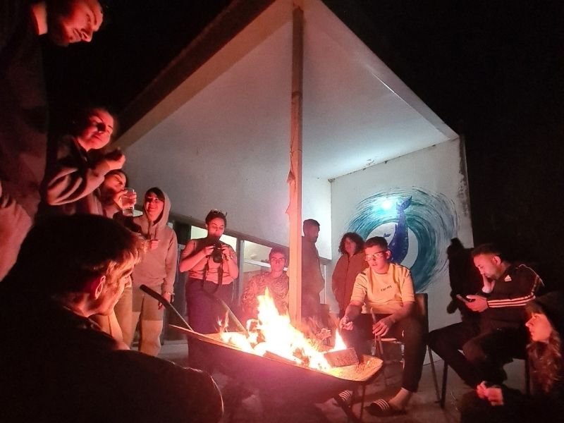Jóvenes reunides alrededor de una hoguera al anochecer, compartiendo un momento de encuentro en Garaldea Ecofeminista durante Focus Pocus.